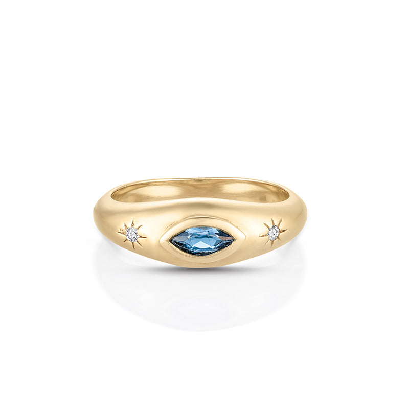 A yellow gold ring featuring a central marquise-cut blue gemstone flanked by two small starburst-shaped clear gemstones, set against a clean white background.
