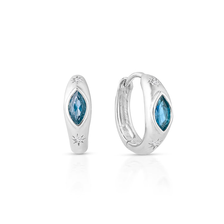 A pair of silver huggie hoop earrings with marquise-cut blue gemstones and small starburst accents, shown on a clean white background.