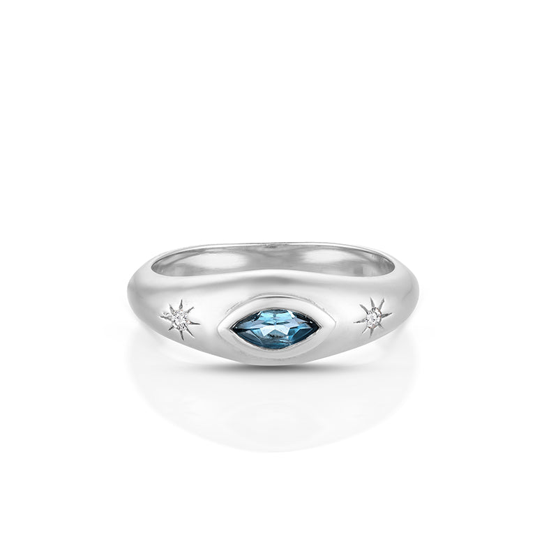 A silver ring featuring a central marquise-cut light blue gemstone surrounded by a starburst motif, with two smaller starburst details on either side of the band, shown on a white background.