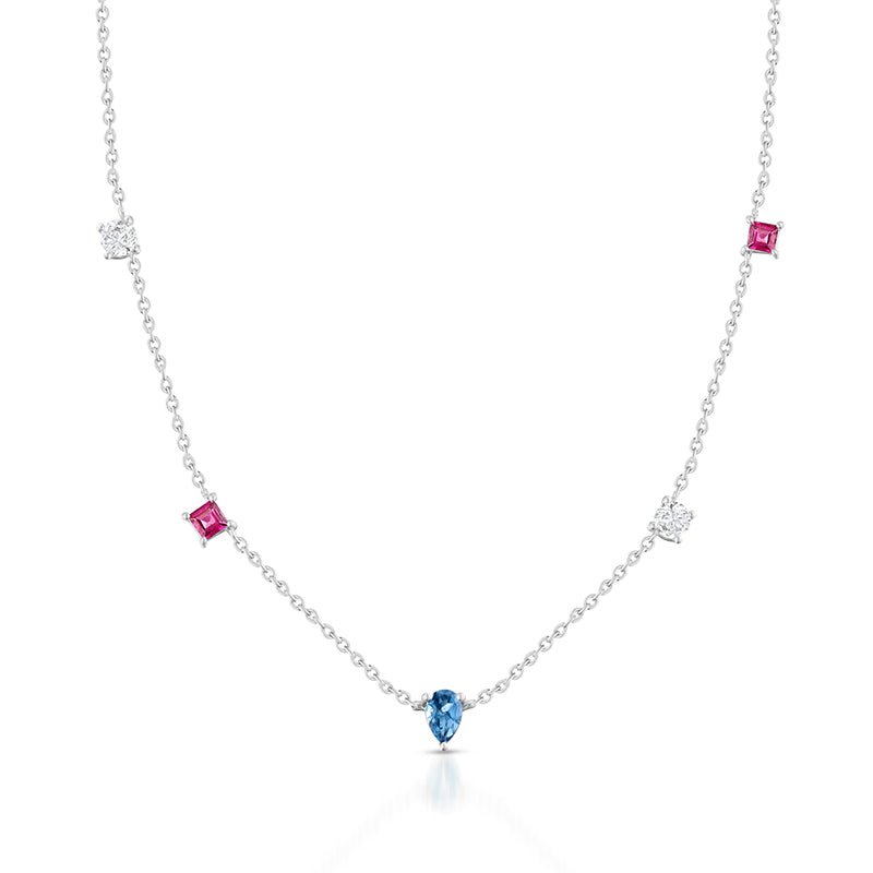 A delicate silver chain necklace featuring a pear-cut blue gemstone at the center, accented by two square-cut pink gemstones and two cluster diamond-like stones on each side, set against a clean white background.