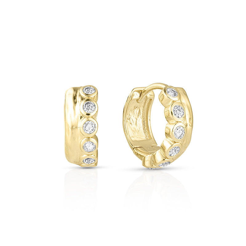A pair of gold huggie hoop earrings with a row of round-cut clear gemstones, shown from the front and side on a white background.