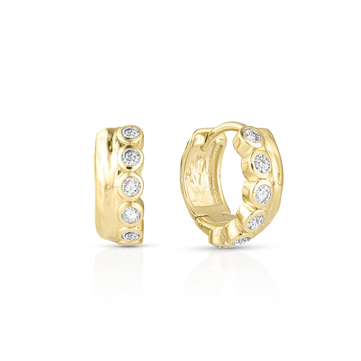 A pair of gold huggie hoop earrings with a row of round-cut clear gemstones, shown from the front and side on a white background.