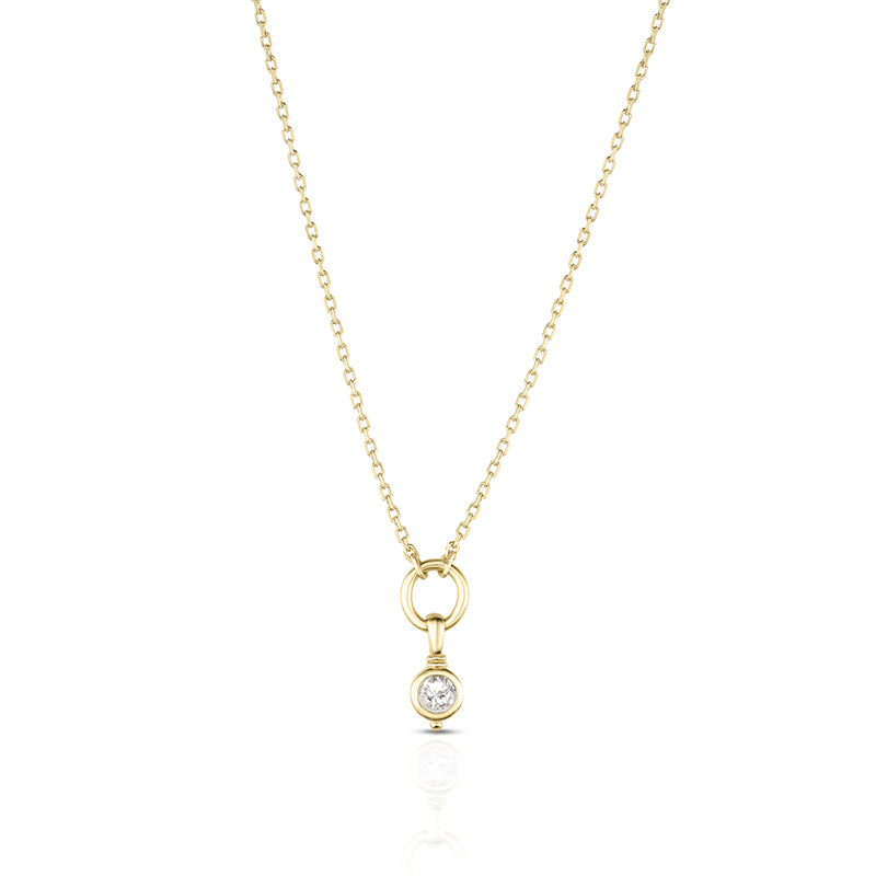 A delicate yellow gold chain necklace with a small ring pendant and a single bezel-set clear gemstone, shown on a clean white background with a soft reflection below.