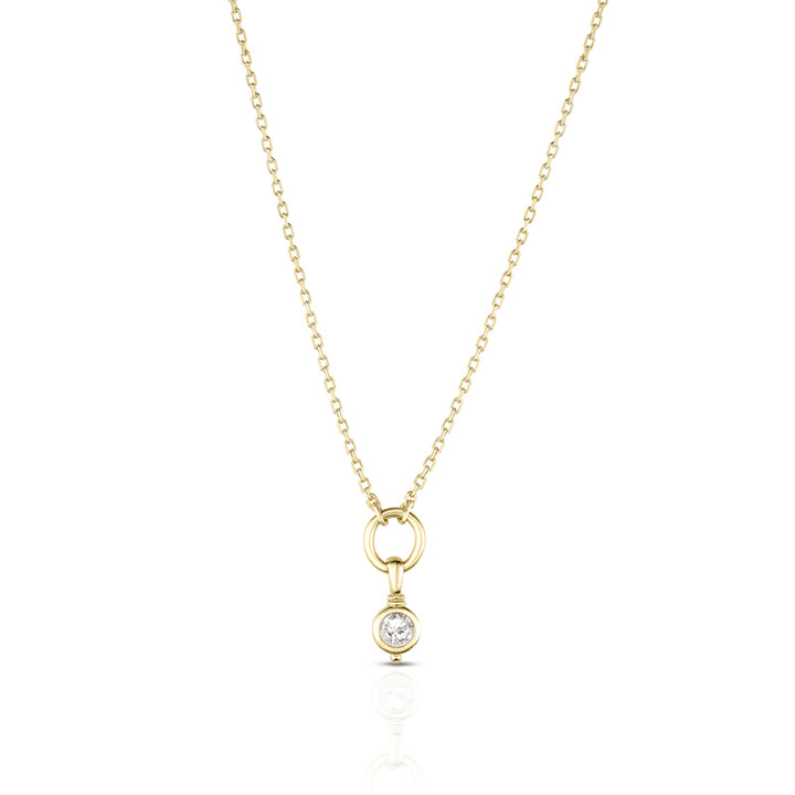 A delicate yellow gold chain necklace with a small ring pendant and a single bezel-set clear gemstone, shown on a clean white background with a soft reflection below.