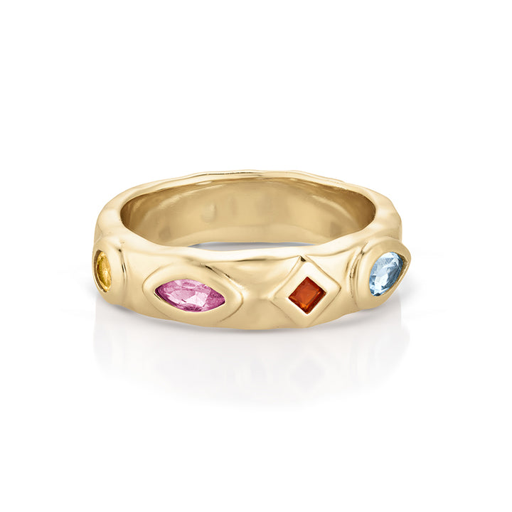 A gold band ring featuring bezel-set multicolor gemstones, including a marquise-cut pink stone, a round orange stone, a round blue stone, and a small yellow stone, shown on a white background.