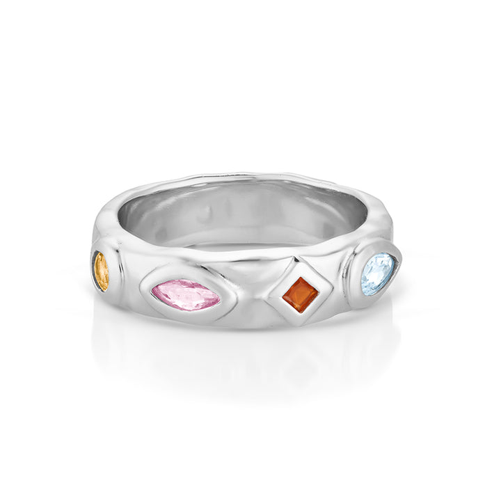 A silver band ring featuring four small, colorful gemstones in different shapes (oval, marquise, diamond, round) set into a textured, wavy silver band, shown on a white background with a soft reflection.