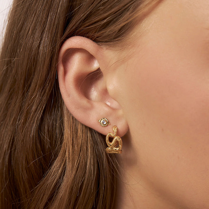 Close-up of an ear wearing gold earrings with a blurred background