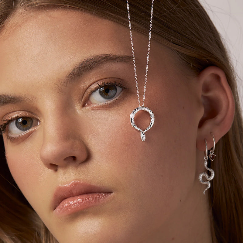 Close-up of a woman wearing silver earrings with a neutral background